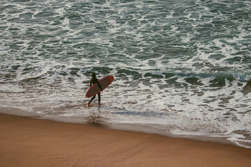 Surfer with surfboard going to surf in a beach