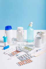 Pills, drops and medicines on doctor table. Uncontrol treatment. Different medicine on white table.