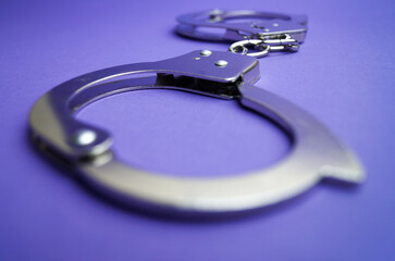Metal handcuffs lie on purple background. Bokeh effect. Favorite blur. Role-playing games.