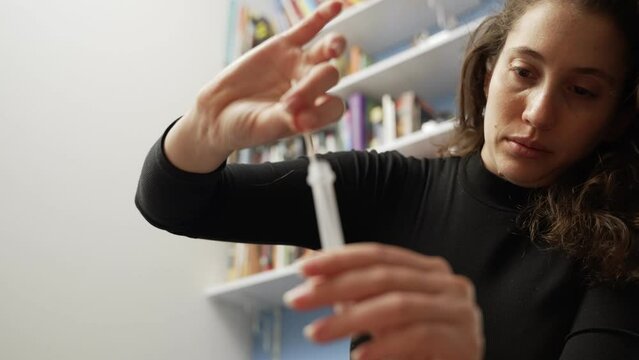 Rapid Covid-19 test at home woman put swab inside tube with liquid to check. After using nasal swab young female verifies for results on coronavirus with antigen home testing kit in living room