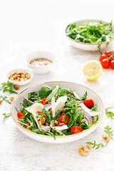 Fresh vegetable salad with arugula, tomato, onion, parmesan cheese and cashew nuts