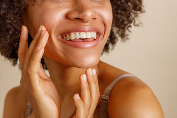 Multiethnic woman toothy smiling on beige background of studio