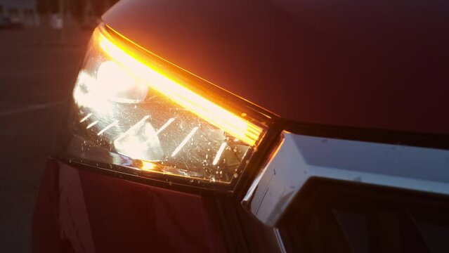 A fast blinking turn signal or blinker of a red car in the evening.