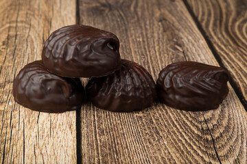 Marshmallows in chocolate on a wooden background.The dessert is delicious.