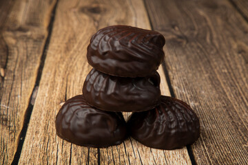 Marshmallows in chocolate on a wooden background.The dessert is delicious.
