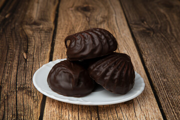 Marshmallows in chocolate on a wooden background.The dessert is delicious.