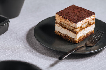 Tiramisu cake dessert served with coffee, biscuit and cocoa as ingredients on a bright white background. One piece
