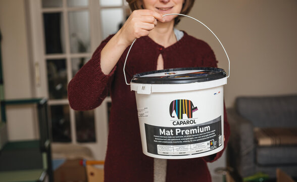 Paris, France - Dec 8, 2021: Front view of young woman holding new plastic package bucket of Caparol Mat Premium luxury German paint
