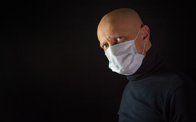 A man in a medical mask on a black background. Precautions against infection with Covid-19,...