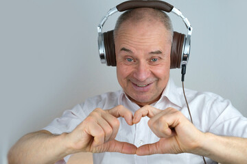 close-up of mature charismatic man 60 years in headphones showing heart with emotions on face...