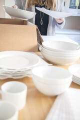 Woman packing white dishes away with white foam sheets