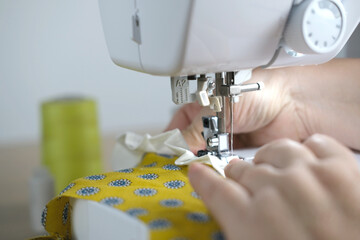 close-up of female hands perform work on a white sewing electric computer machine, stitches appear step by step on the fabric, concept of tailoring, women's hobby, modern needlework
