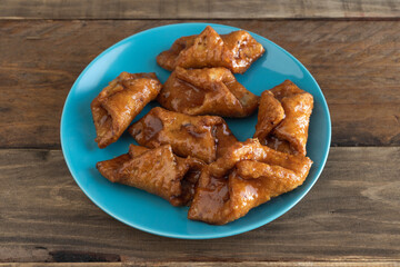 Pestiños. Typical sweet of Christmas and Easter. Carnival fried sweets in blue plate on wooden background.