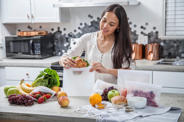 A woman packs fresh fruit, vegetables and food into clear storage bags