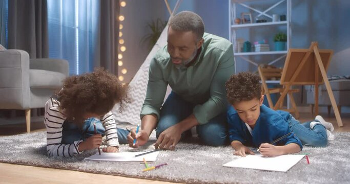 Close up of happy african american grandfather spending weekend with two grandchildren and helping little boy draw picture.