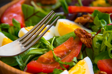green salad, egg, tomato in a plate on a wooden background