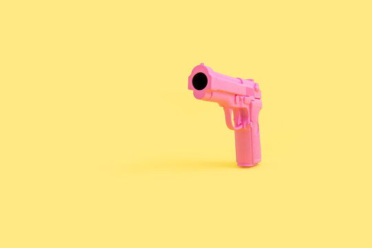 Pink toy gun on yellow background