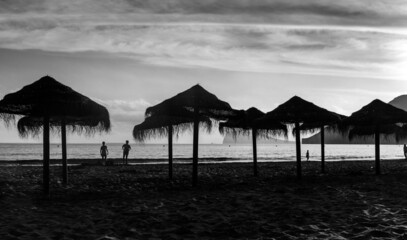 silhouette de parasols sur la plage au coucher du soleil en noir et blanc