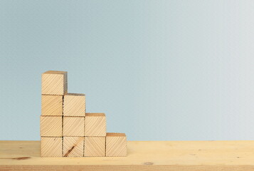 Wooden cubes stacked in the shape of a ladder without graphics on the background of a textured gray wall, the concept of business growth and teamwork, a symbol of leadership, a template for design