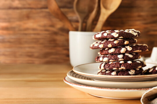 Plates of tasty cookies with white chocolate chips on wooden background