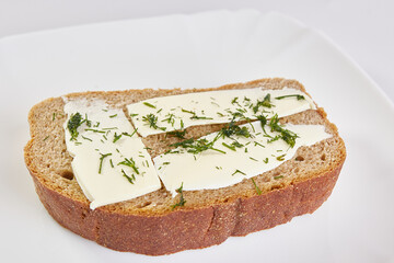 Sandwich of rye bread, butter and greens.