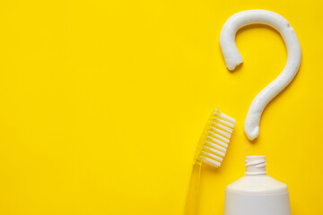 Toothbrush, opened tube and question mark on color background