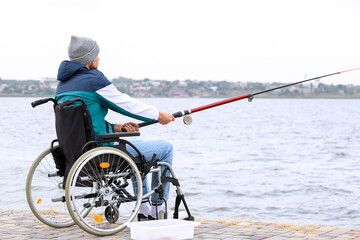 Man in wheelchair fishing on river