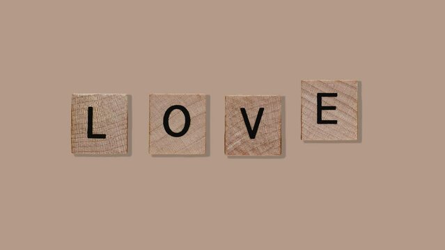 Natural wood texture cubes on love text on Noise craft paper color background, valentine card concept. Word of love are made of letters from wood for your girlfriend for Valentines Day greeting card 