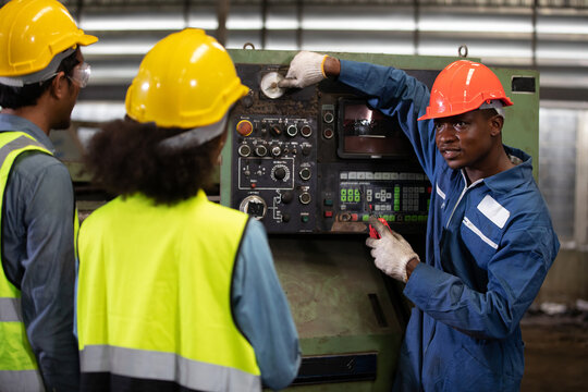 male african foreman training and teaching how to use machine control with workers in factory