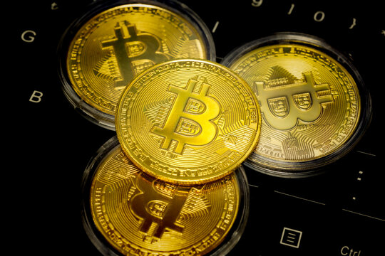 Symbolic three gold bitcoin coins with bitcoin symbol on laptop keyboard keys. Bitcoin coin in the middle in selective focus. Cryptocurrency, stock market, blockchain, digital money concept.