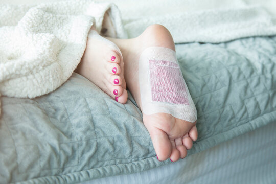 Woman's Feet In Bed With Foot Detox Pads On