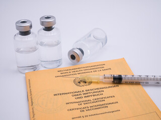 Yellow certification of vaccination with vaccine containers and syringe with white background - 482928792