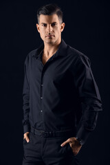 Portrait of fashionable gentleman keeping hands in pockets on dark background