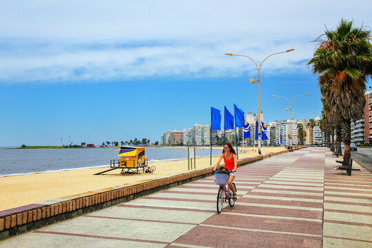 Woman biking on the boulevard along Pocitos beach in Montevideo, Uruguay.