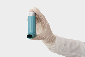 Woman holding asthma inhaler on light background