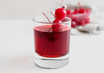 Glass of tasty Manhattan cocktail with cherries on light background, closeup