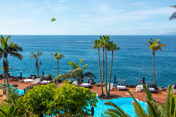 Beach club with blue swimming pool and palm trees on coast of Atlantic ocean, Costa Adeje, Tenerife, Spain