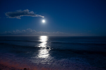 Moonlight path on water of Atlantic ocean at night on Tenerife and dark blue sky with full Moon and...