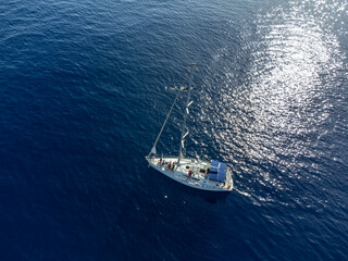 Aerial top view on dark blue water of Atlantic ocean and white sailboat with tourists