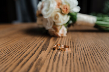 Wedding bouquet of fresh flowers, a pair of gold rings close-up. Wedding details