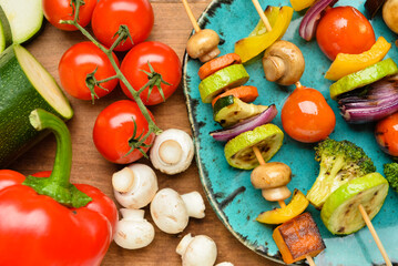 Tasty vegetable skewers on wooden background, closeup