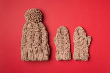 Brown winter hat and mittens on color background. Top view