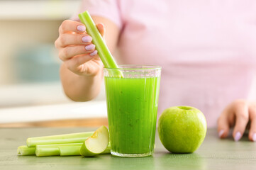 Woman preparing healthy green juice at kitchen table, closeup