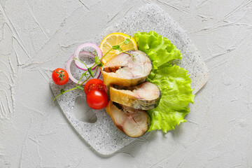 Board with pieces of smoked mackerel fish on light background