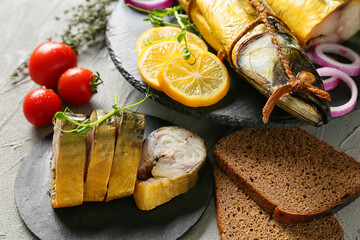 Board with pieces of smoked mackerel fish and bread on table