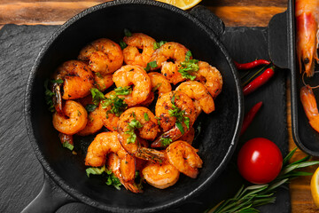 Frying pan of tasty shrimp tails on table