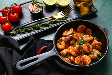 Frying pan of tasty shrimp tails and tomatoes on table