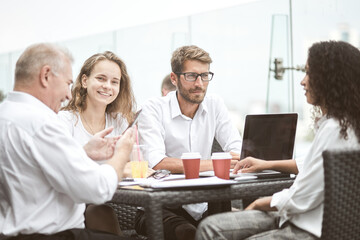 Fototapeta premium Smiling colleagues working together developing business strategy for their next project. Young casually dressed business people having discussion on sunny terrace. Modern job in comfortable conditions