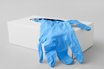 Paper box with medical gloves on light background, closeup