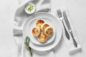 Plate with tasty cottage cheese pancakes and sauce on white background